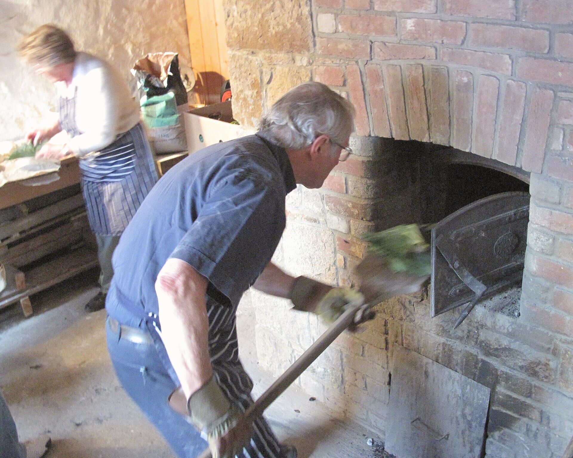 Bakker schuift brood in een houtgestookte oven